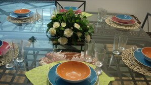 Ett matbord dukat med flera skålar, glas och en bordsdekoration bestående av vita blommor.