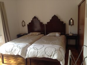 A double bed with a wooden headboard, two bedside tables, and a nightstand with a lamp.