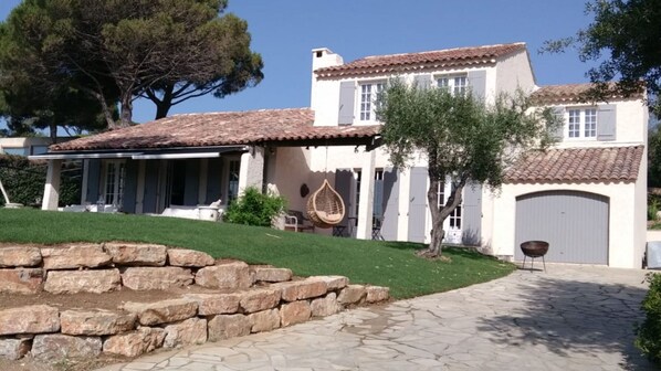Une maison à deux étages, avec un toit en tuiles, un mur de pierre à l’avant et une allée pavée.