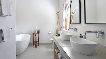 A modern bathroom with a freestanding bathtub, two large sinks, and a mirror above the sinks.