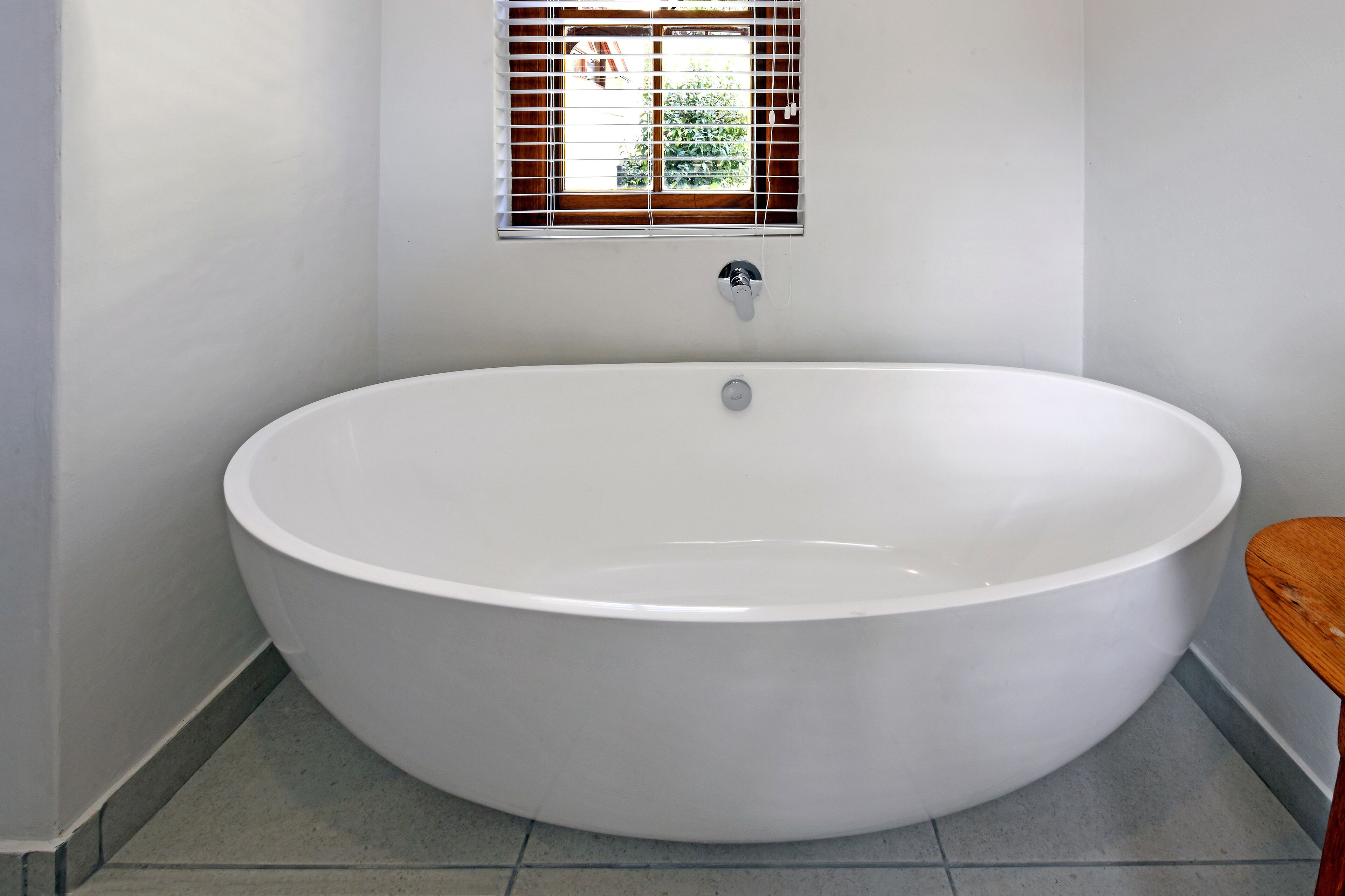 A large, oval-shaped bathtub in a bathroom with a window above it.