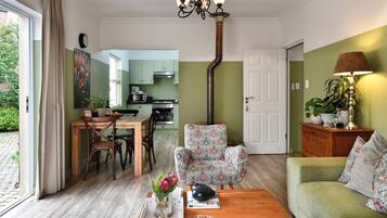 A living room with a sofa, a coffee table, a patterned armchair, and a dining area with a table and chairs.