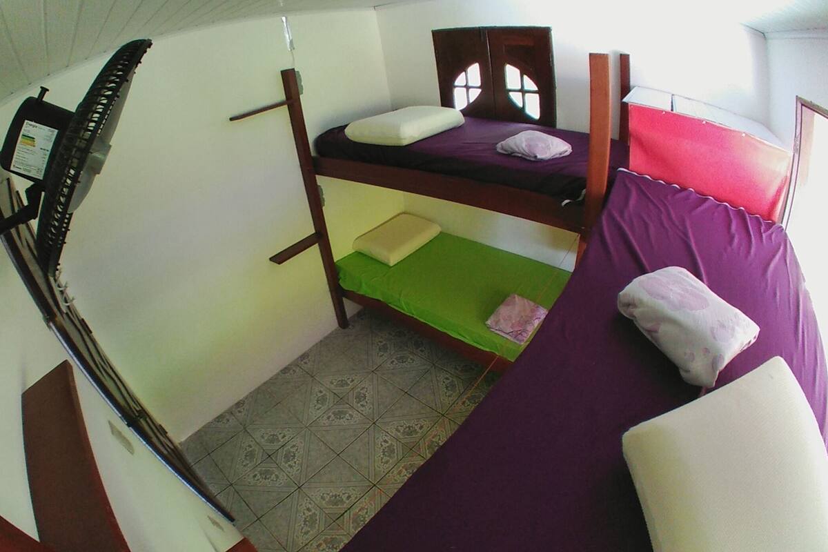 Dormitorio con literas, un escritorio pequeño y una silla, una ventana con vistas y suelo de baldosas.