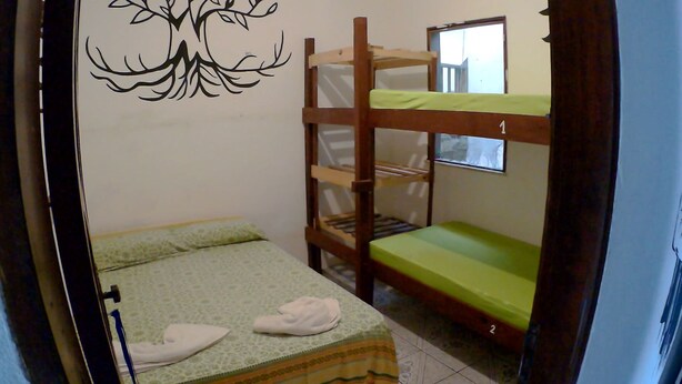 Een kleine, compacte kamer met stapelbedden, een enkel bed en een wanddecoratie.