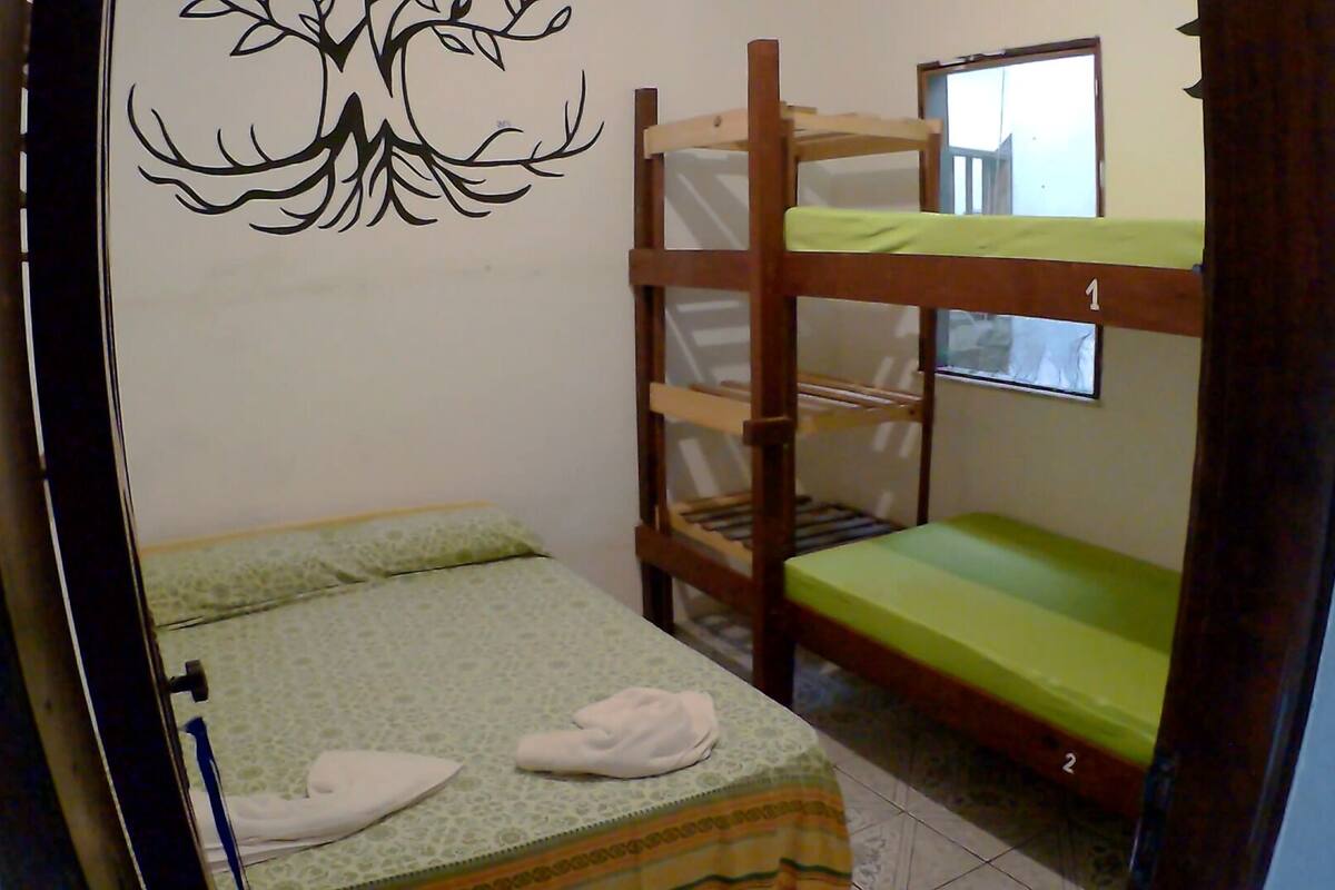 Habitación pequeña y funcional con literas, una cama individual y un adorno en la pared.