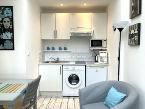 A compact kitchen with a washing machine, microwave, and coffee maker.