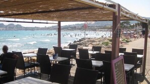 Un espace extérieur aménagé avec des tables et des chaises, offrant une vue sur la plage.