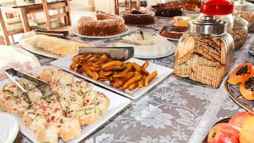 A buffet table with various dishes including cakes, pastries, and fruits.