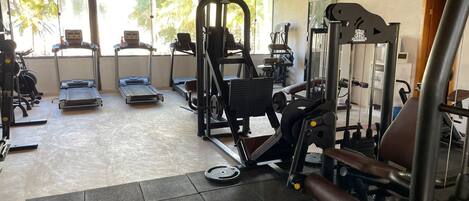 A gym with treadmills, weight machines, and a mirror.