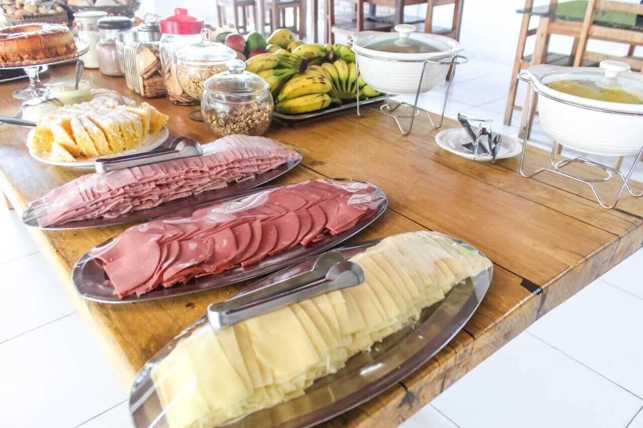 A buffet table with various food items including sliced meats, a cake, and bananas.