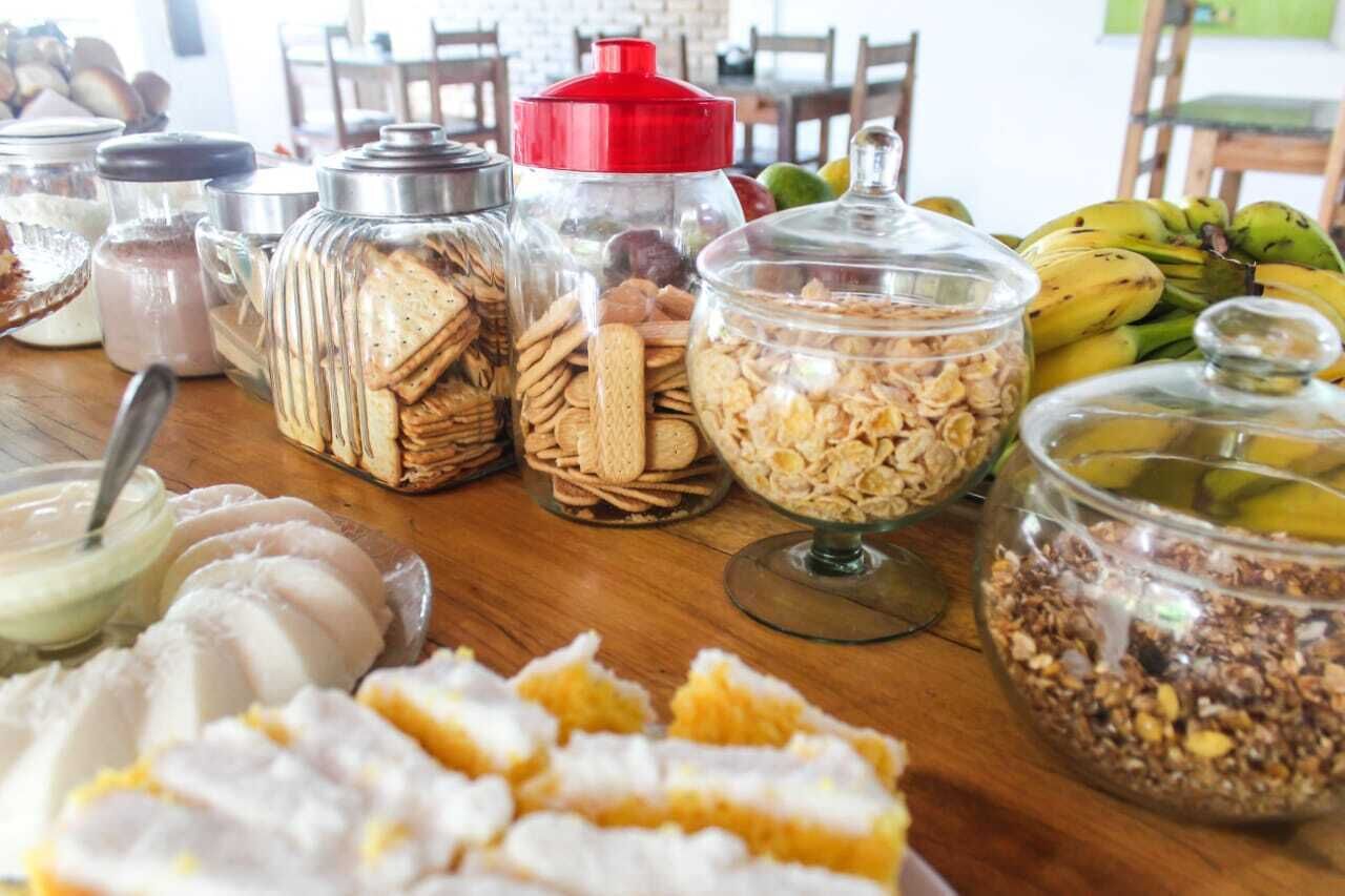 Ett urval av livsmedel, inklusive burkar med nötter, kex och müsli, på ett träbord.