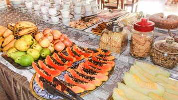 Una mesa de buffet con diversas frutas, pasteles y bebidas.