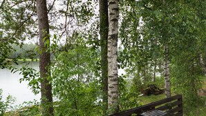 A wooden bench and table in a wooded area with a lake in the background. - Köningsviken vacations in Sipoo (Sibbo)