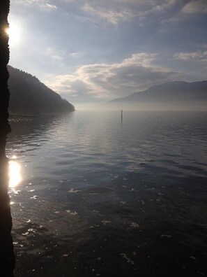 Ein ruhiger See mit Bergen im Hintergrund und einem klaren Himmel.