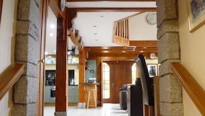A stone archway leading to a wooden staircase with a kitchen and living area in the background.