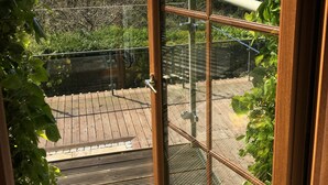 A view from a room with a large window overlooking a wooden deck and a garden.