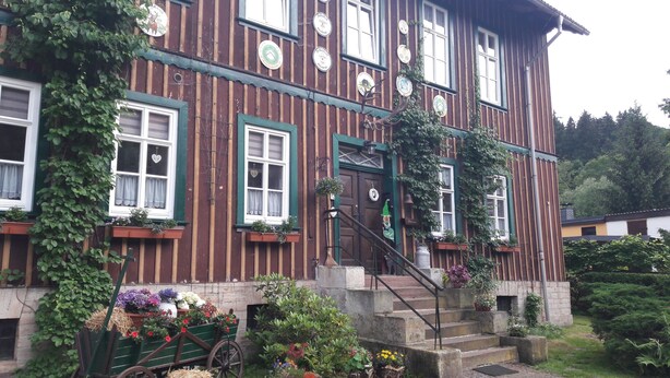 A traditional wooden building with multiple windows, a front door, and a staircase leading to the entrance.