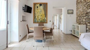 A modern room with a dining area, a stone wall, and a painting of a woman.