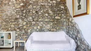 A room with a stone wall, a white sofa, a small table, and a white cabinet with decorative items.