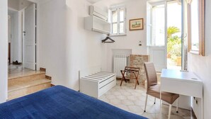 A bedroom with a bed, a desk, a chair, a radiator, and a window.