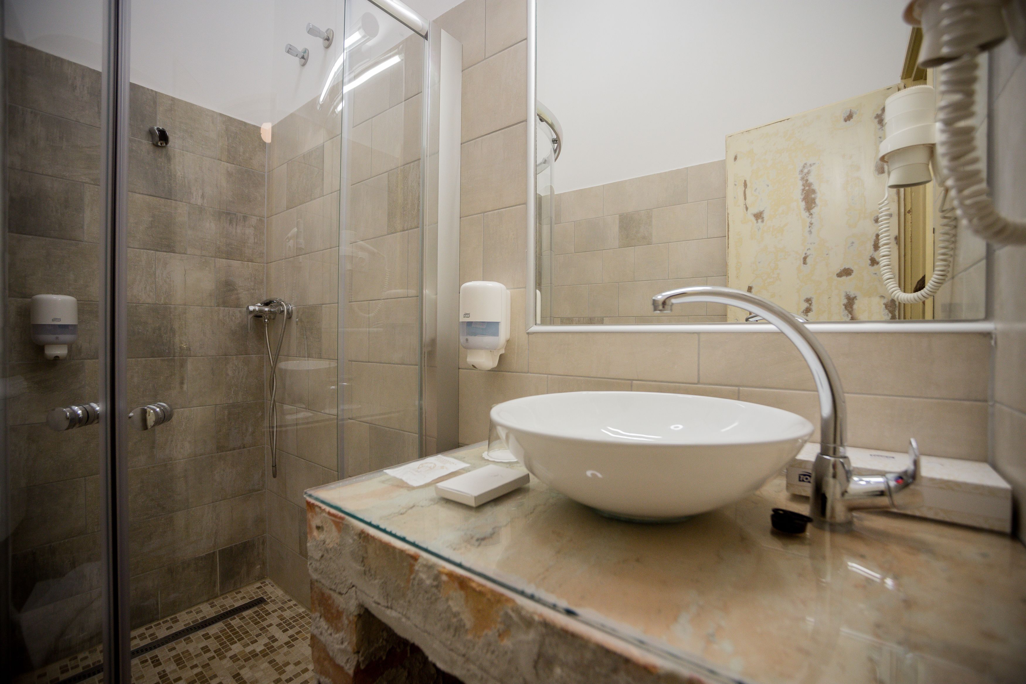 A bathroom with a glass-enclosed shower, a white sink, and a mirror.