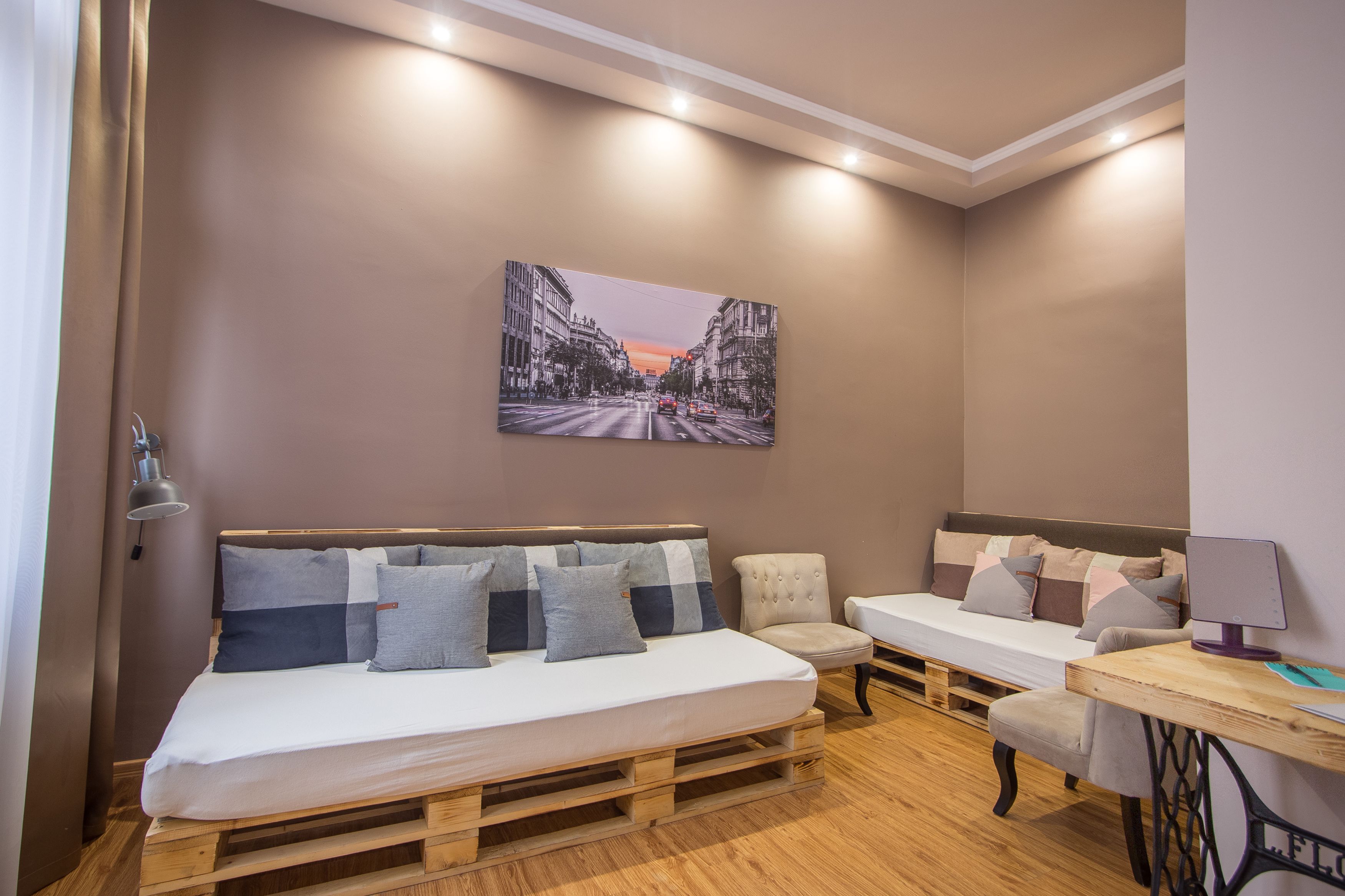 Ein modernes Schlafzimmer mit einem hölzernen Bett, einem kleinen Sofa, einem Schreibtisch und einem Stadtbild an der Wand.
