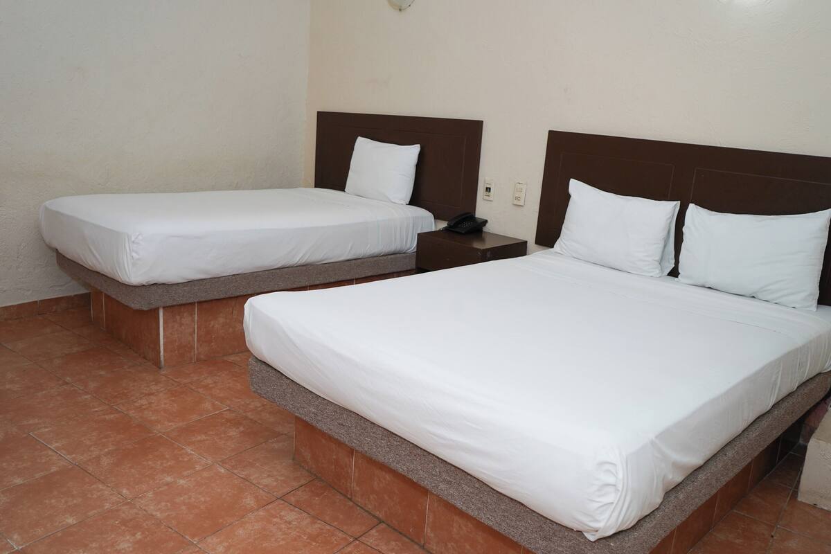 Een hotelkamer met twee bedden, elk met witte beddengoed en houten hoofdborden.