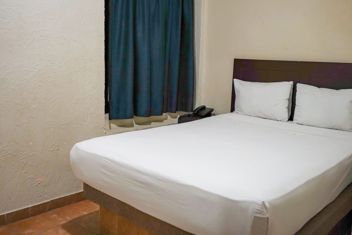 Een keurig opgemaakt bed met witte lakens in een hotelkamer.