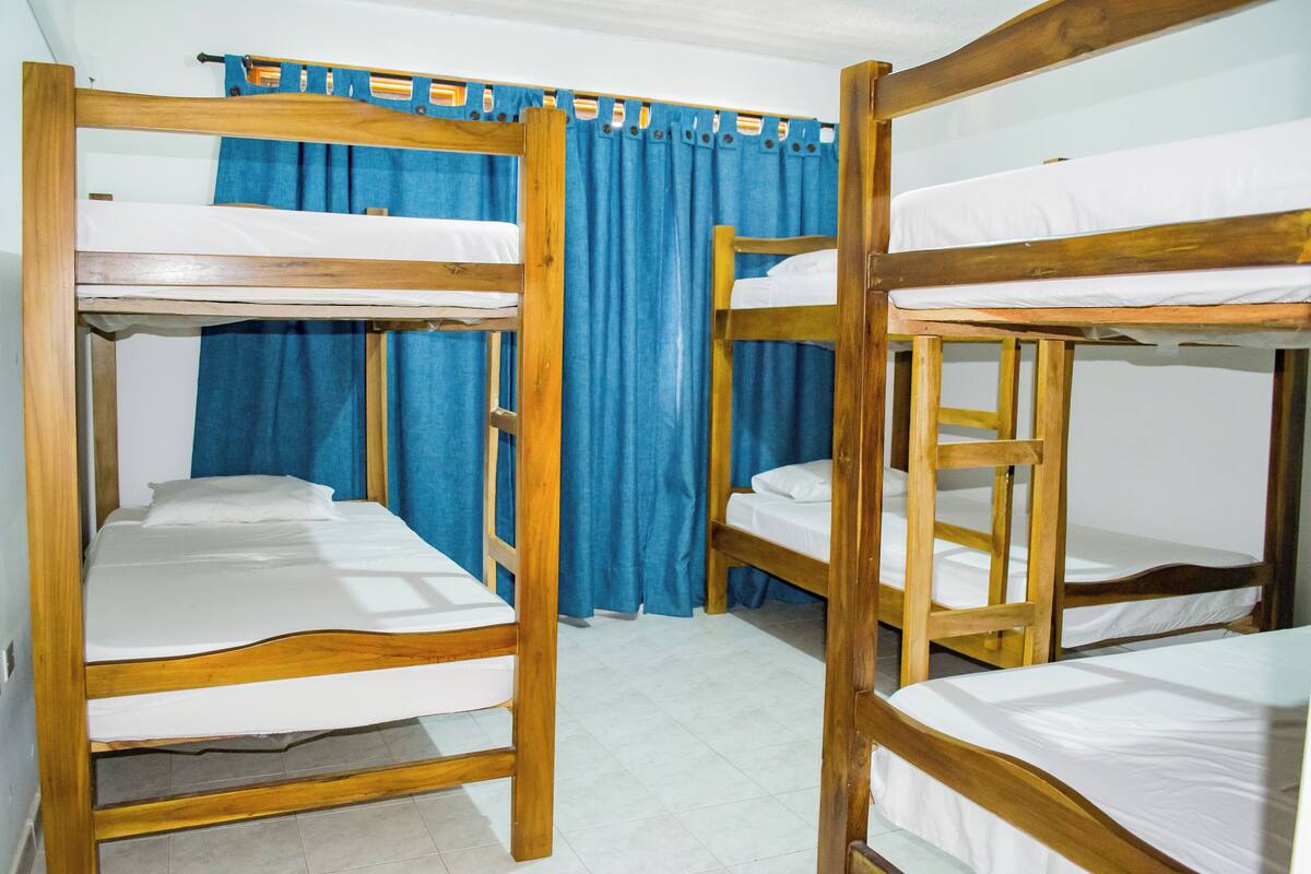 A room with bunk beds, blue curtains, and white bedding.