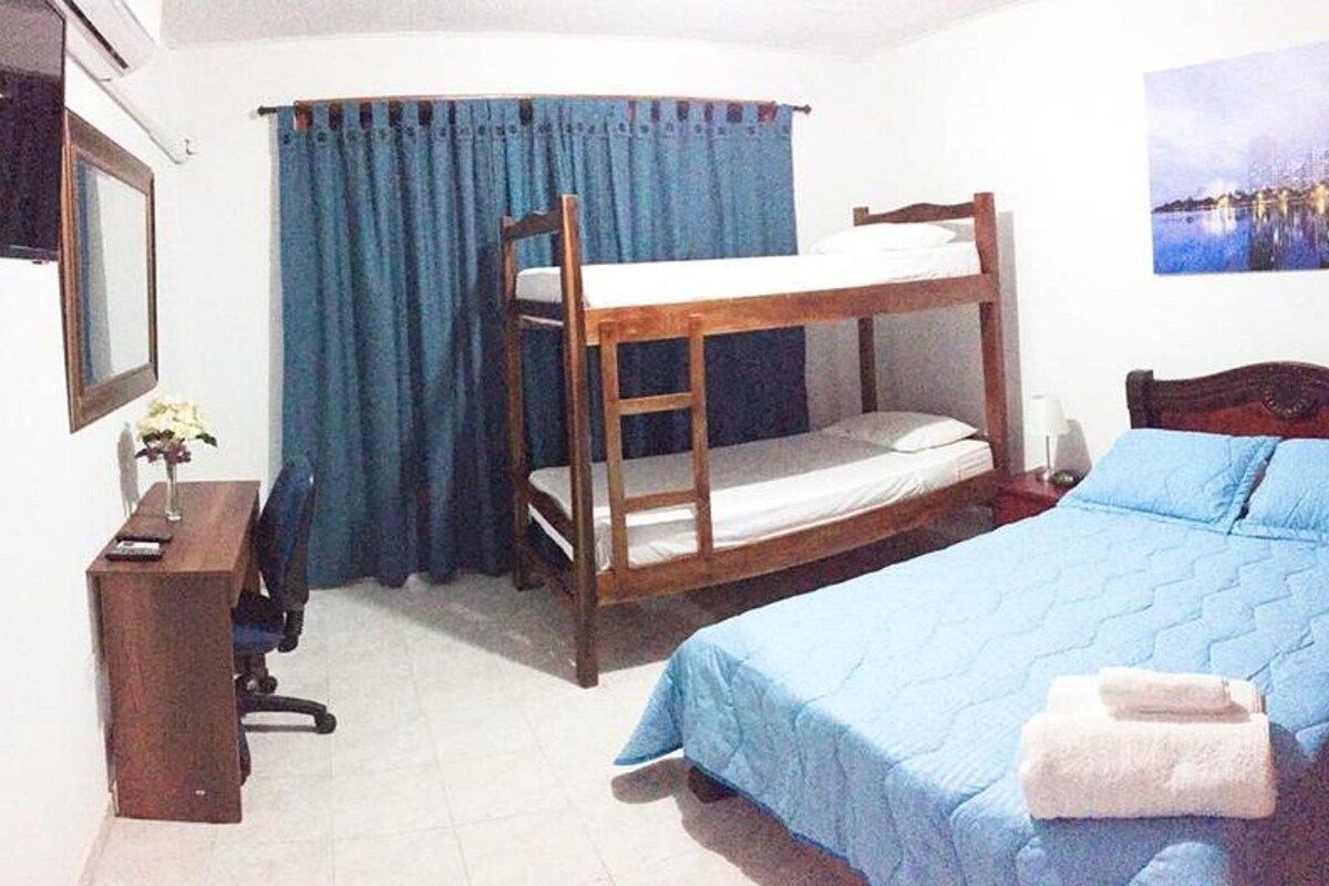 A room with bunk beds, a desk, a chair, a lamp, and a painting on the wall.