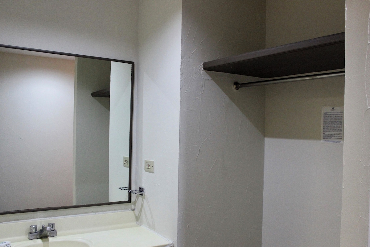 A bathroom with a white sink, a mirror, and a towel rack.