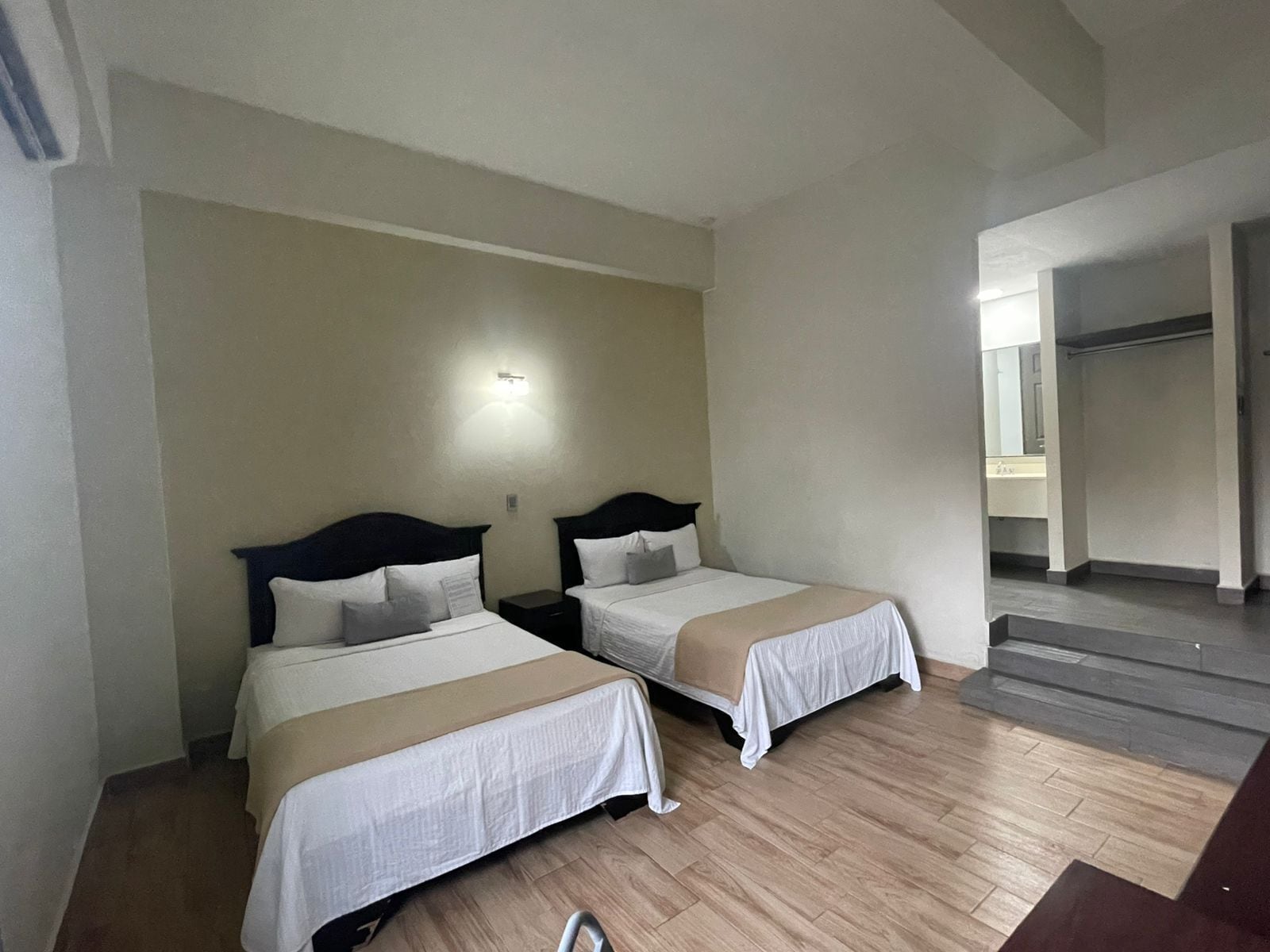 Habitación de hotel con dos camas, una lámpara y una escalera que lleva a un baño.