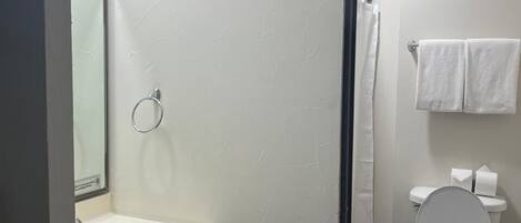 A bathroom with a toilet, sink, and shower area.