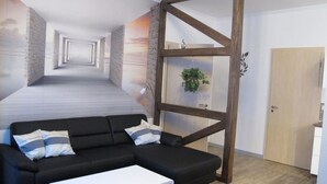 Un soggiorno moderno con un divano a sezione nero, una finestra con cornice in legno e una porta.