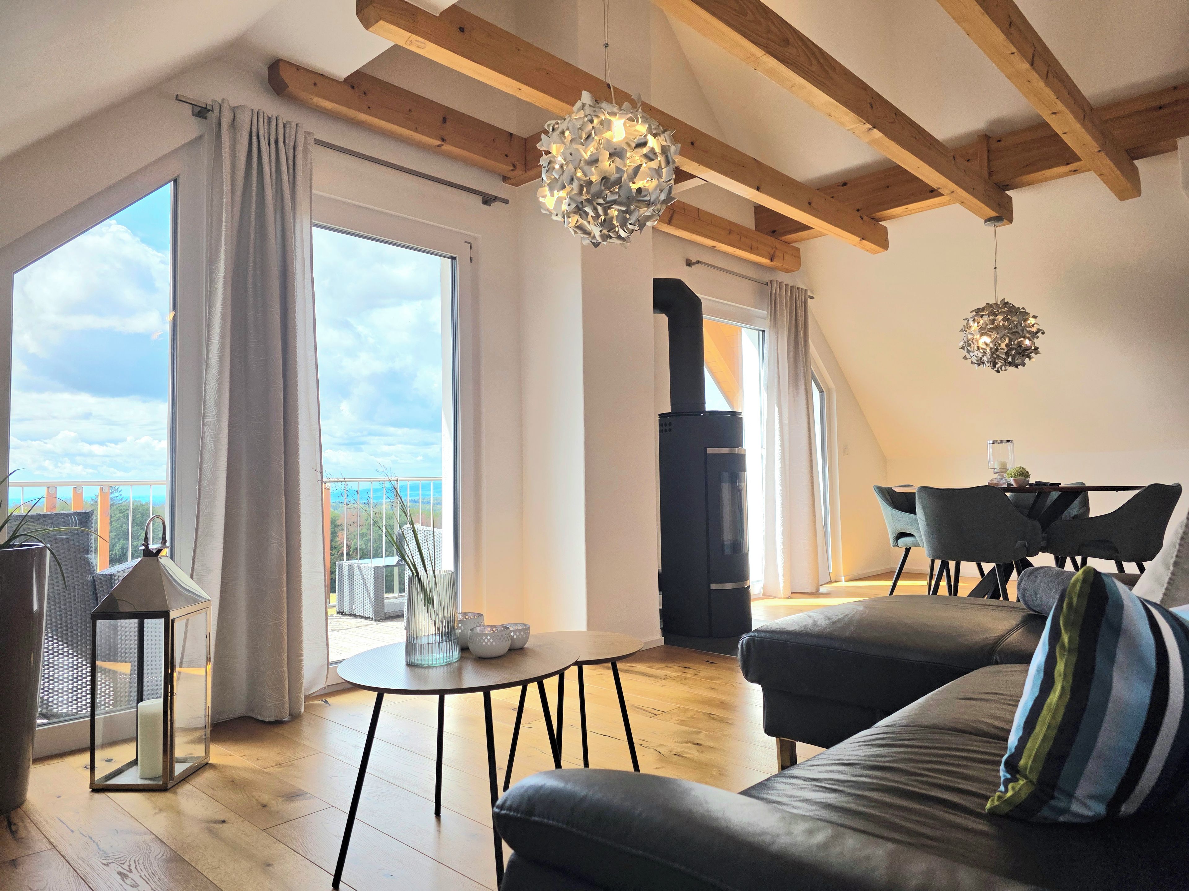 Ein modernes Wohnzimmer mit Kamin, großen Fenstern und einem Essbereich.