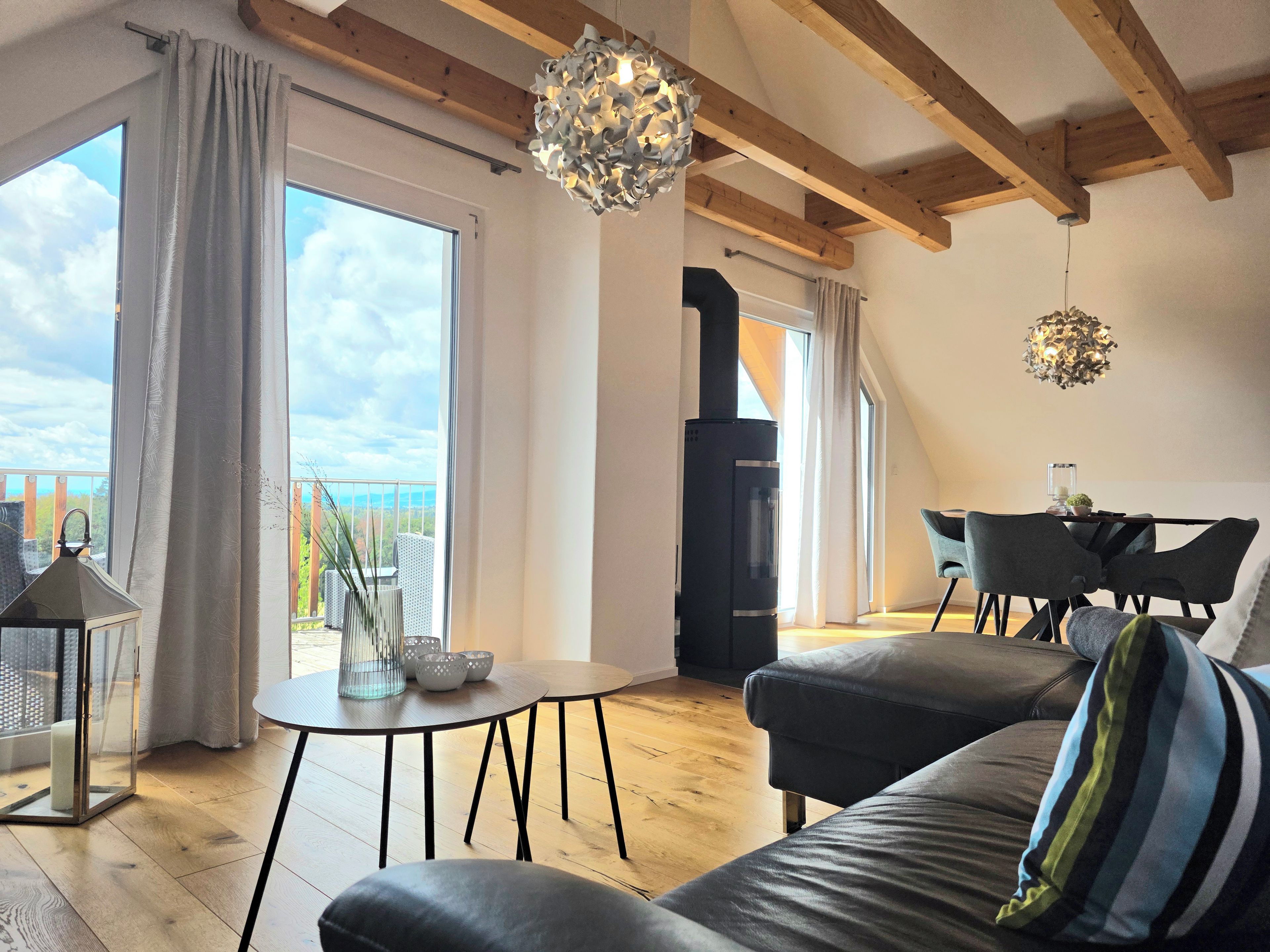 Ein modernes Wohnzimmer mit Kamin, großen Fenstern und einem Essbereich.