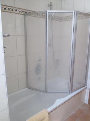 Et brusekabine med glasvægge og et badekar.
