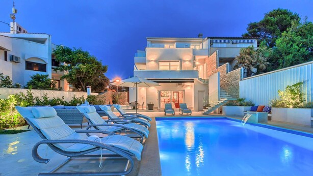 Un área de piscina moderna con sillones de descanso y una piscina azul cristalina.