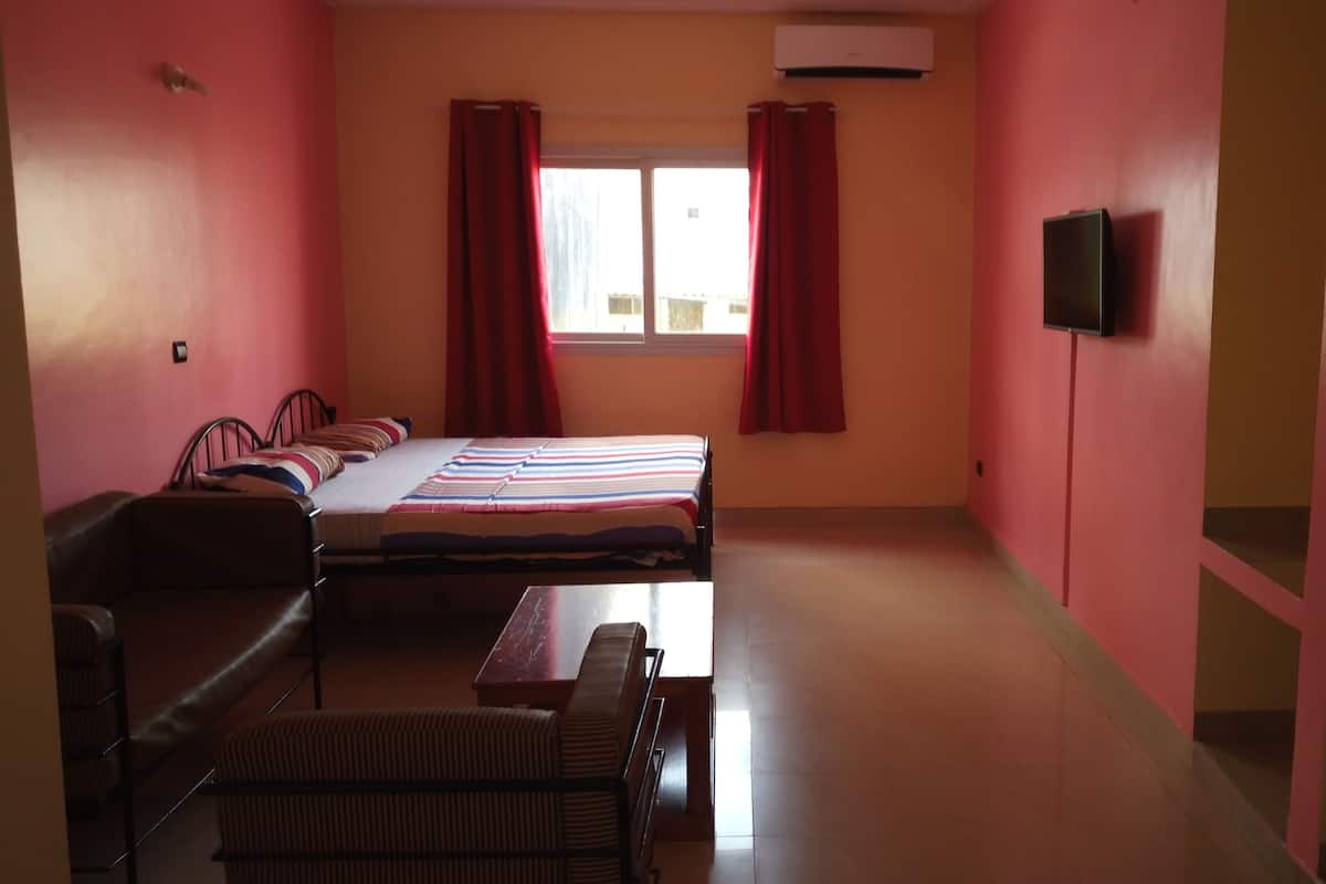 A hotel room with two beds, a desk, a chair, a TV, and a refrigerator.