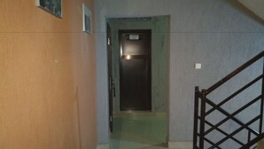 Um corredor estreito com uma porta identificada como "CHAMBRE N°31" que dá para um elevador.