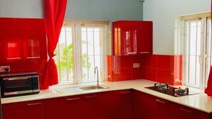 Une cuisine avec des meubles de rangement rouges, une cuisinière à gaz et un four à micro-ondes.