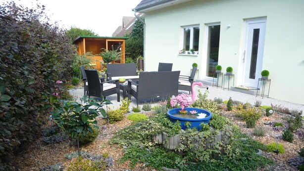 A garden with a dining area, a flamingo sculpture, and a crocodile sculpture.