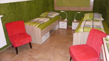 Een slaapkamer met twee bedden, een rode stoel en een groene muur.