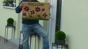 A person holding a welcome sign with flowers.