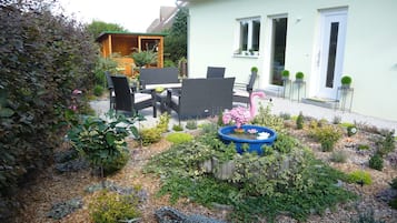 Een tuin met een eethoek, een flamingo beeldhouwkunst en een krokodil beeldhouwkunst.