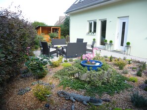 Un jardín con una zona de comedor, una escultura de flamenco y una escultura de cocodrilo.
