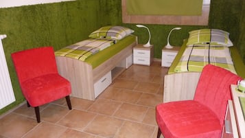 Een slaapkamer met twee bedden, een rode stoel en een groene muur.