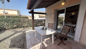 A patio with a table and chairs, a pergola overhead, and a sliding glass door leading to an indoor area with a table and chairs. - Spacious 3-Room Villa with Mezzanine, Pool & Parking - Close to Richelieu Beach (Cap d'Agde)