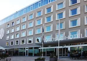 Een modern hotel met een opvallend bord, meerdere ramen en een glazen ingang.