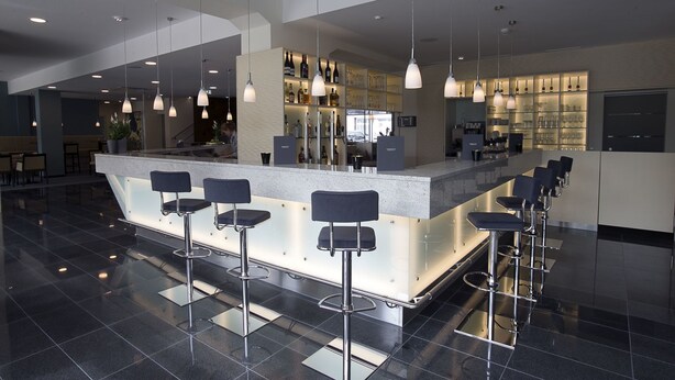 Zona de bar moderna con una isla central y taburetes.